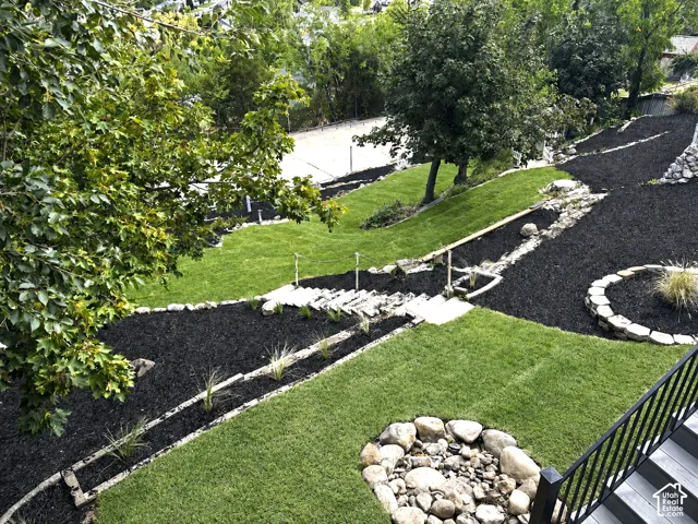 Tiered landscaping with expansive green lawn, natural stone steps, and decorative rock features