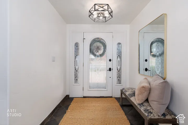 Entryway featuring a decorative front door with arched glass and sidelights, dark tile flooring, and a contemporary geometric flush-mount light fixture