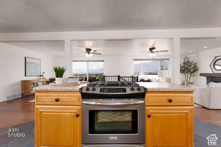 Kitchen island featuring a stainless steel range, light wood-finish cabinetry, and a light-toned countertop