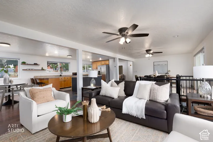 Expansive open-concept living area featuring dark wood-finish flooring, multiple ceiling fans, and recessed lighting