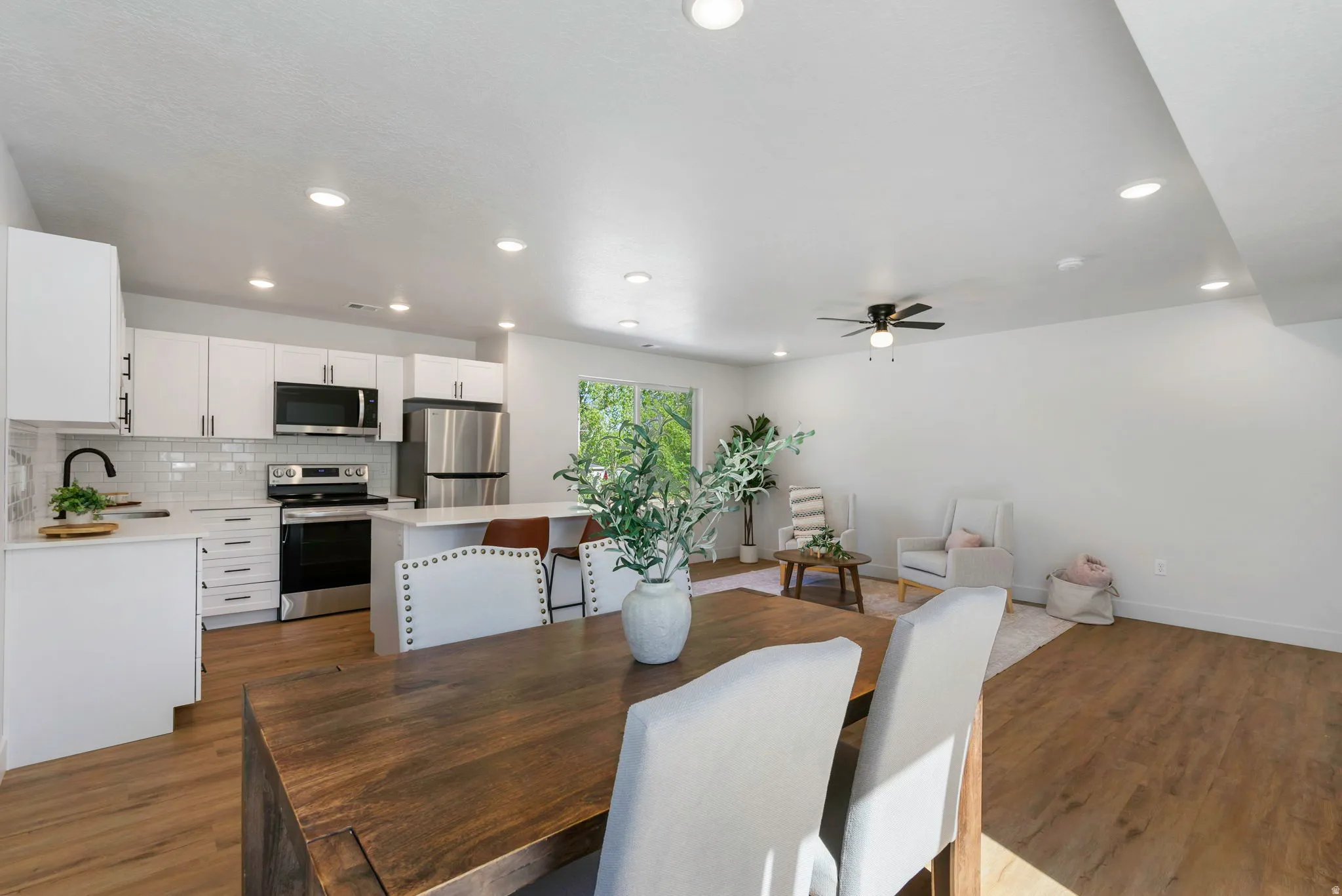 Open-concept living area featuring wood-finish flooring, recessed lighting, and a modern ceiling fan