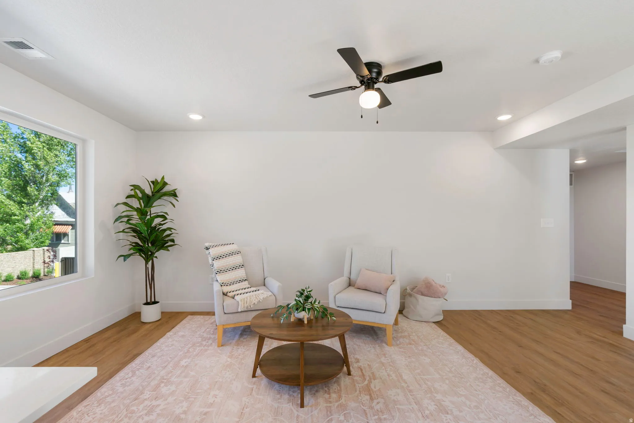 Bright living area featuring wood-finish flooring, recessed lighting, a modern ceiling fan, and a large picture window