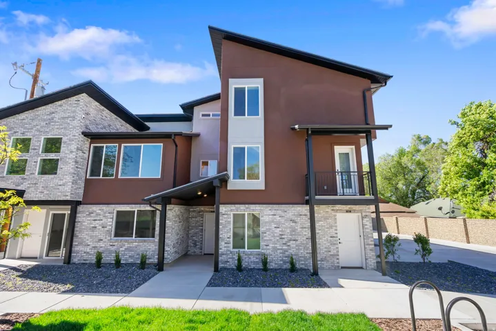 Modern multi-level exterior featuring light gray brick, brown stucco, and a striking black-trimmed roofline