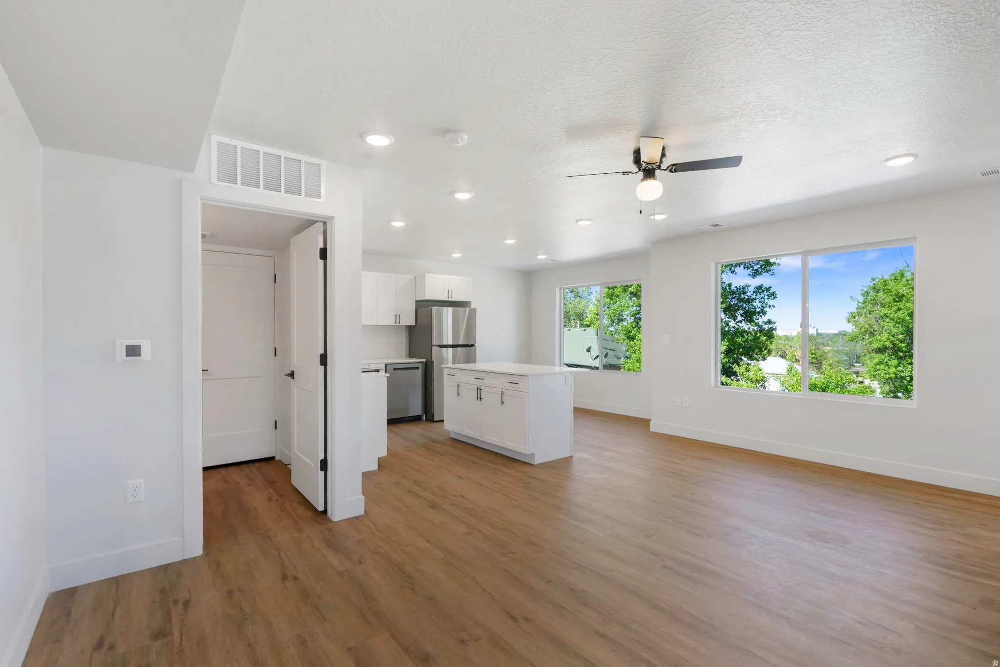 Open-concept living space featuring wood-finish flooring, recessed lighting, and large windows