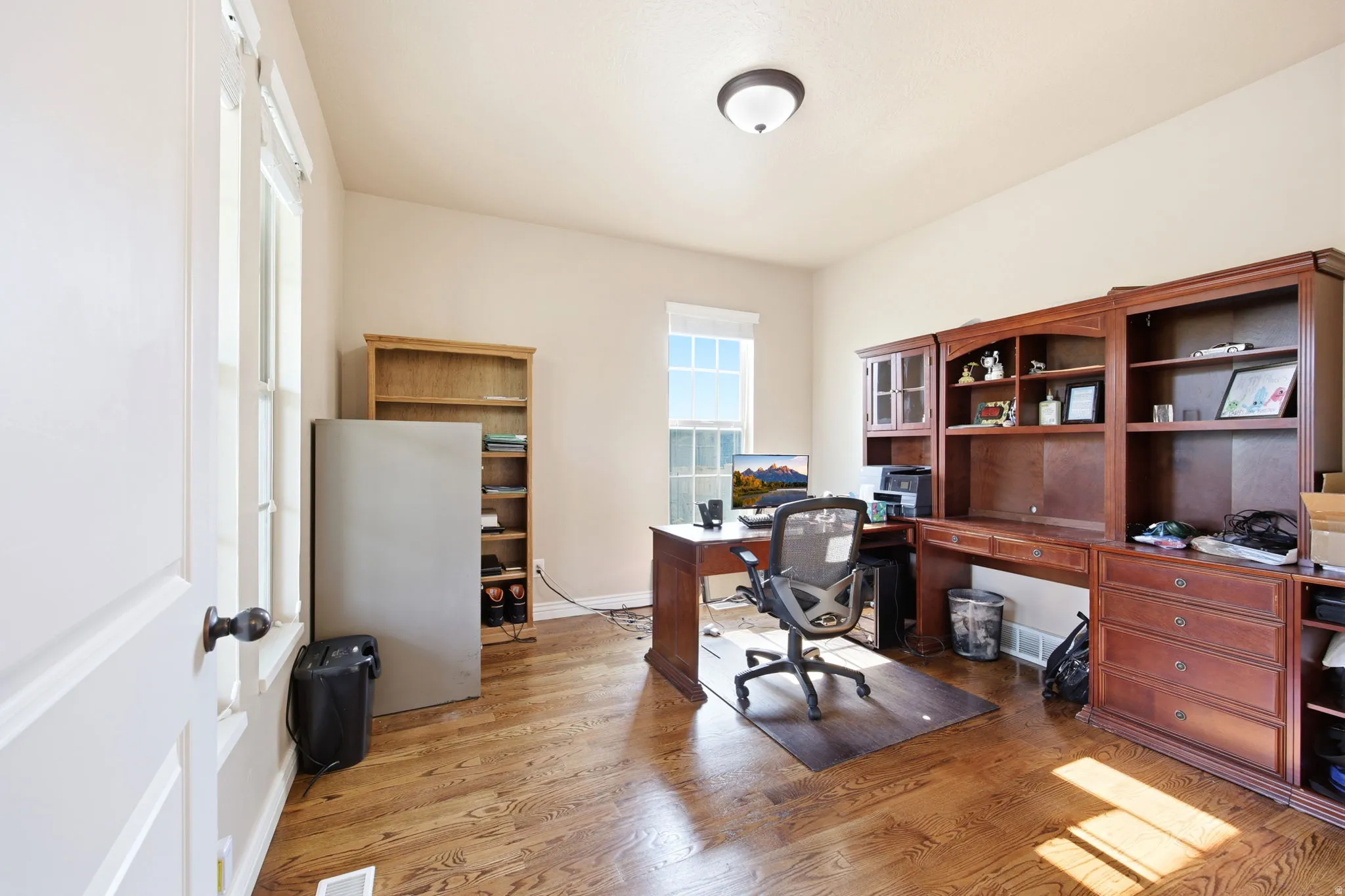 Room featuring wood-finish flooring, a double-paned window, and a built-in wood-finish shelving unit