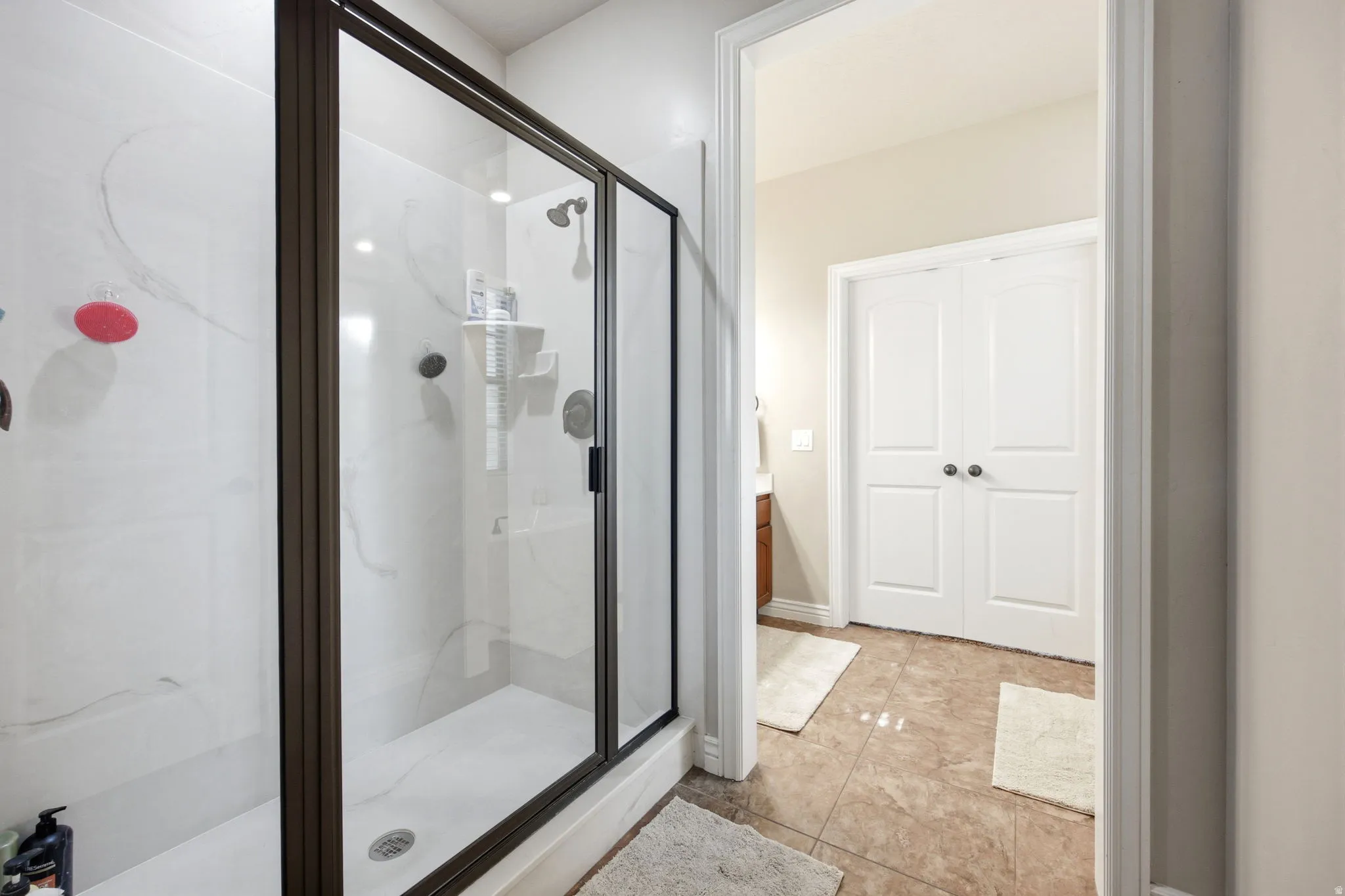 Enclosed shower with a dark bronze frame, clear glass panels, and white tile surround