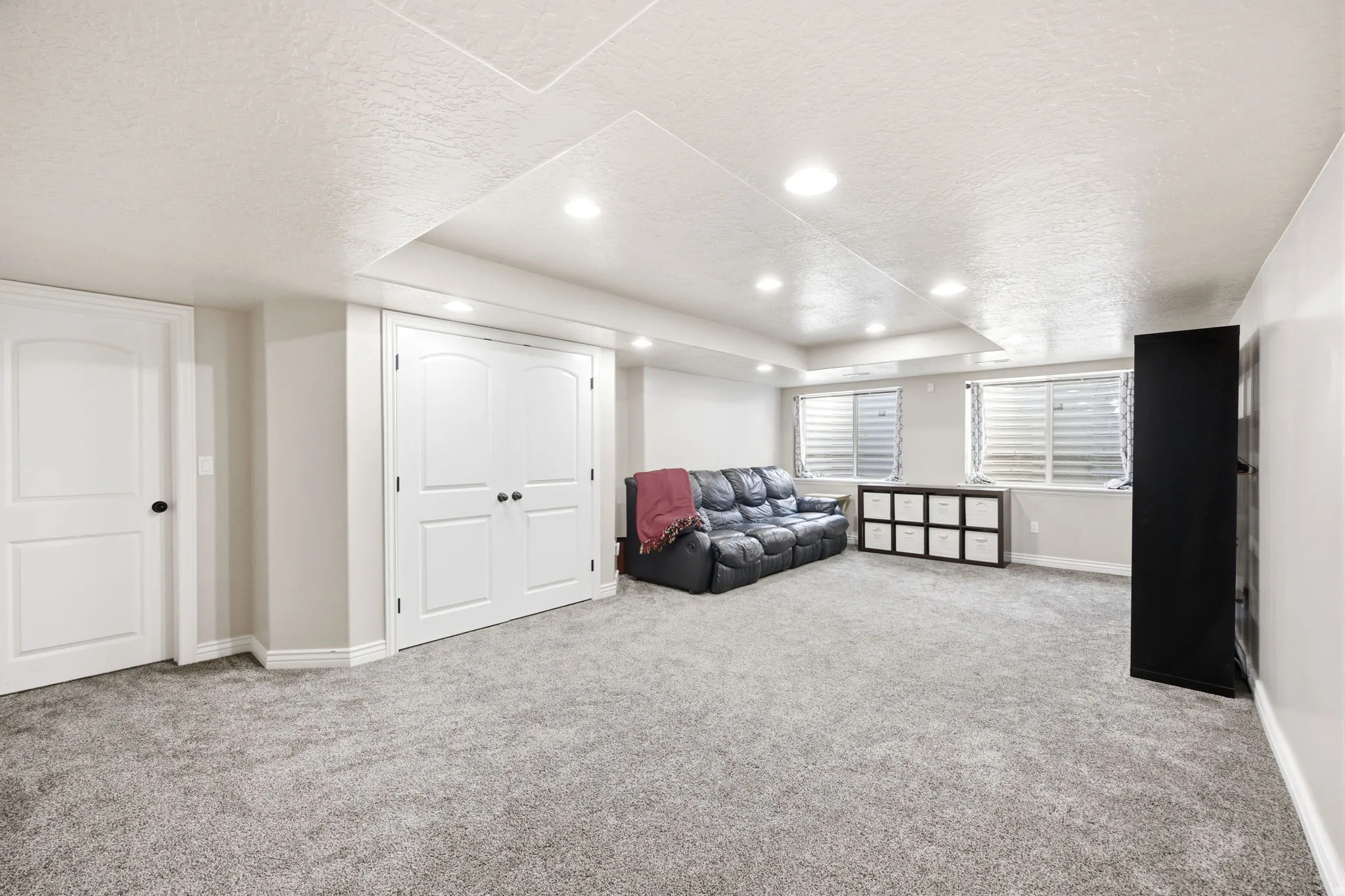 Spacious carpeted room featuring recessed lighting and two windows with horizontal blinds