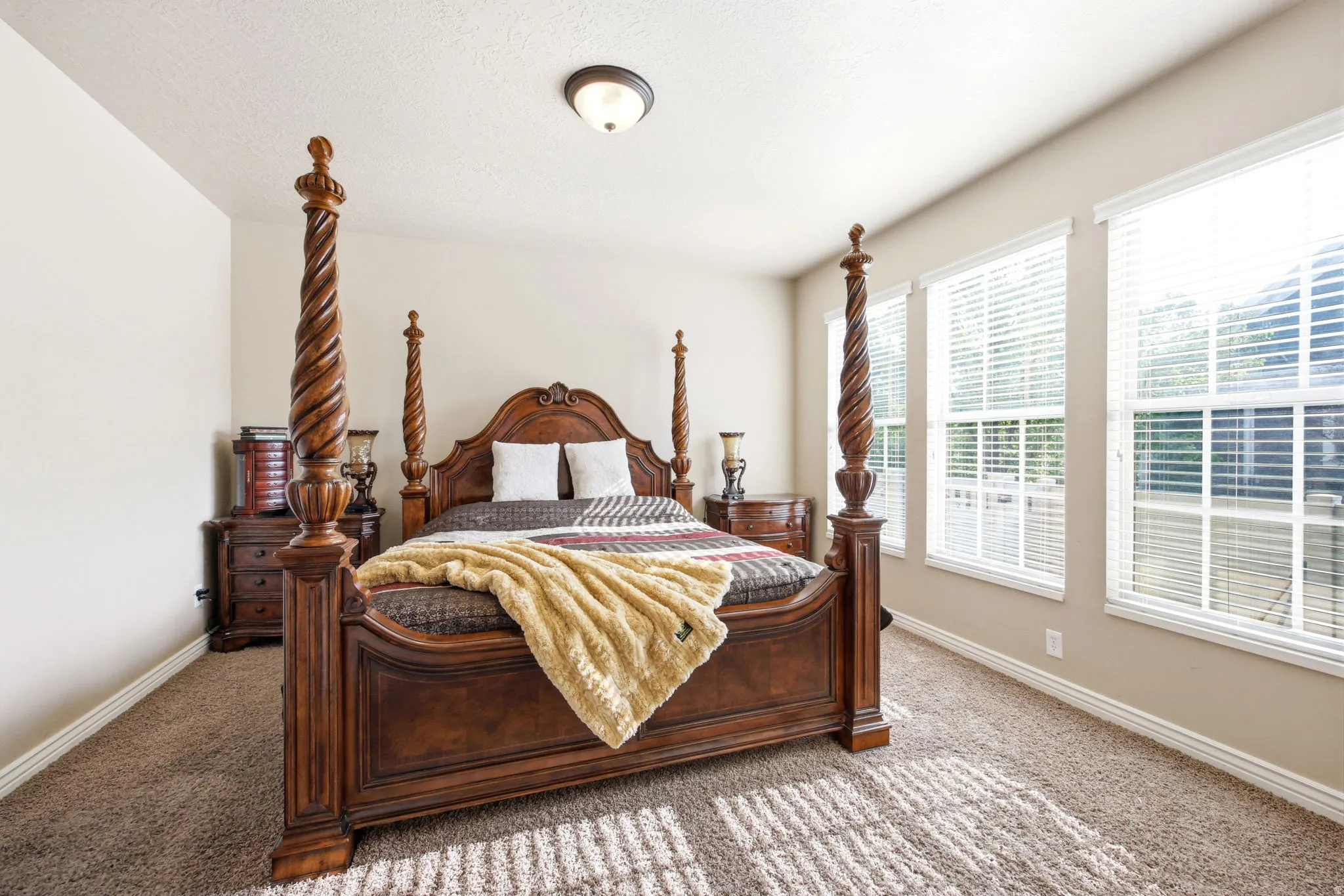 Plush carpeted room featuring multiple windows with blinds, a neutral wall color, white trim, and a ceiling-mounted light fixture