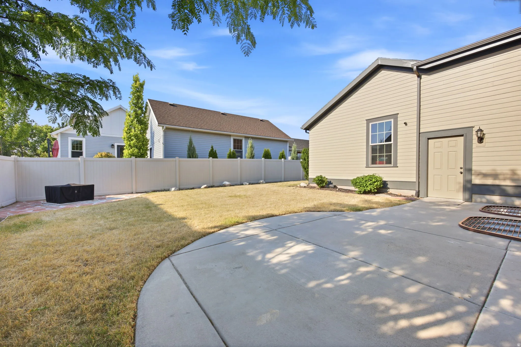 Private backyard featuring a concrete patio, a section of brick paving, and a perimeter vinyl fence