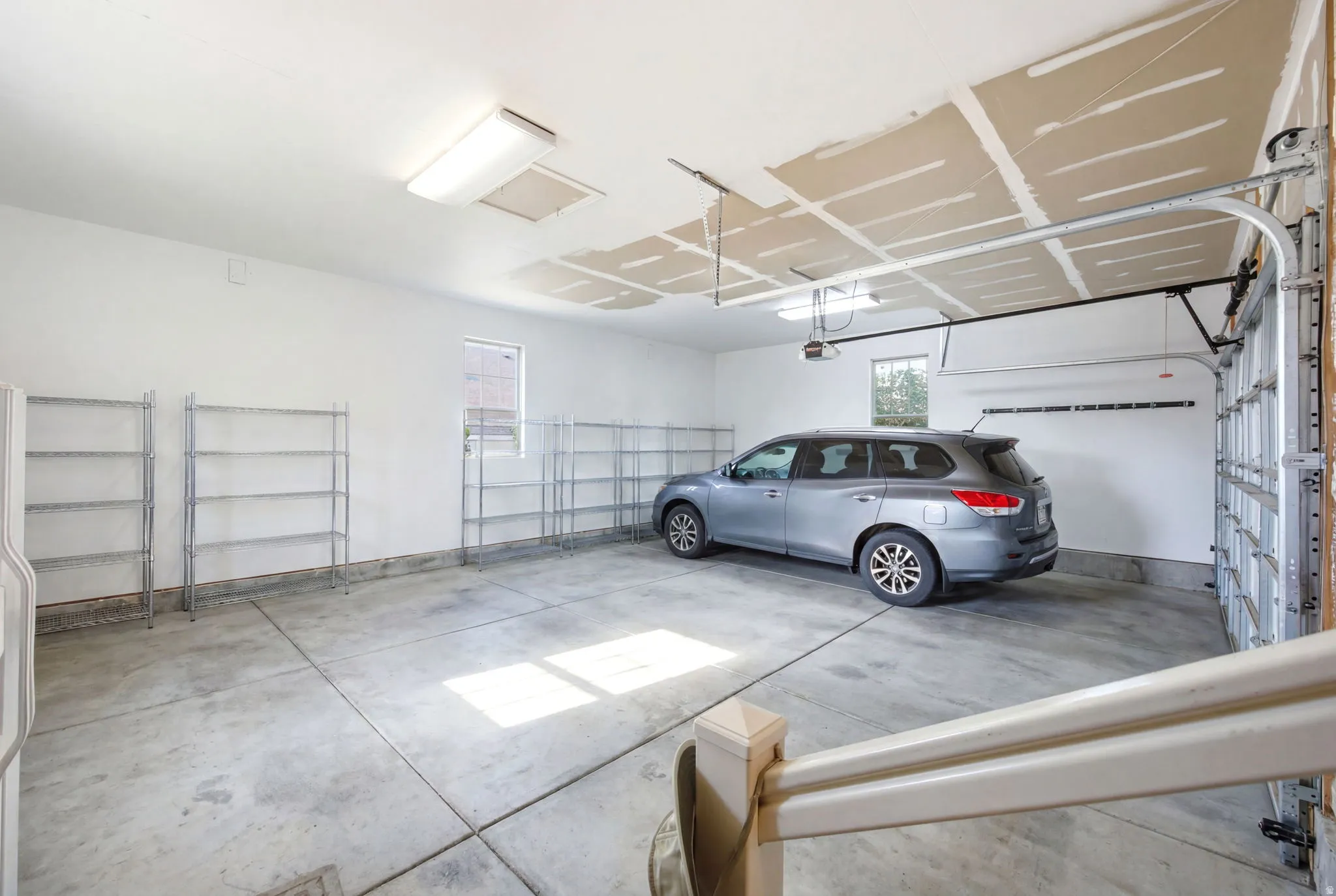 Spacious garage featuring a concrete floor, bright white walls, and a large overhead garage door