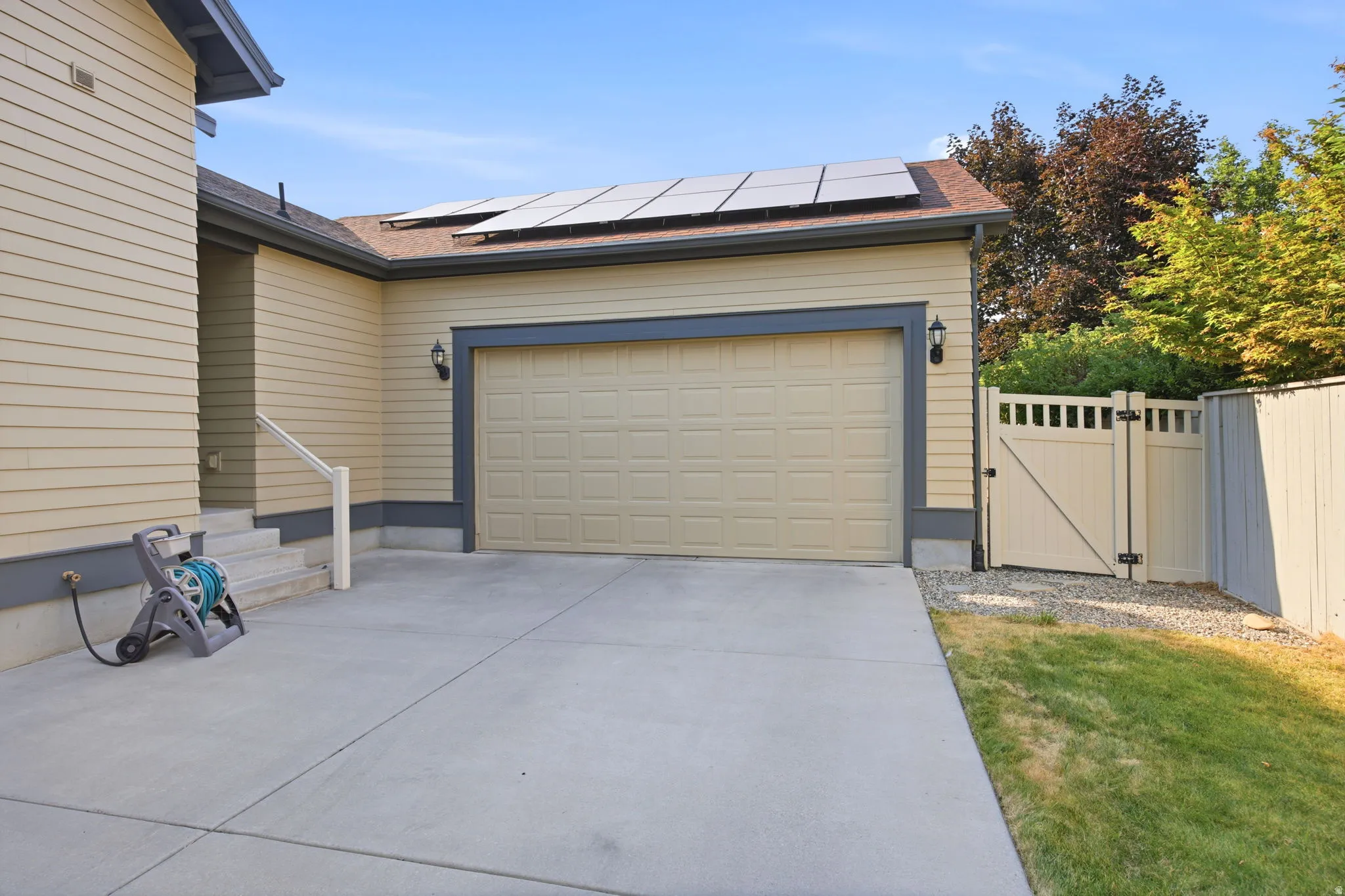 Two-car garage with a panel door, featuring flanking wall sconces and solar panels on the roof