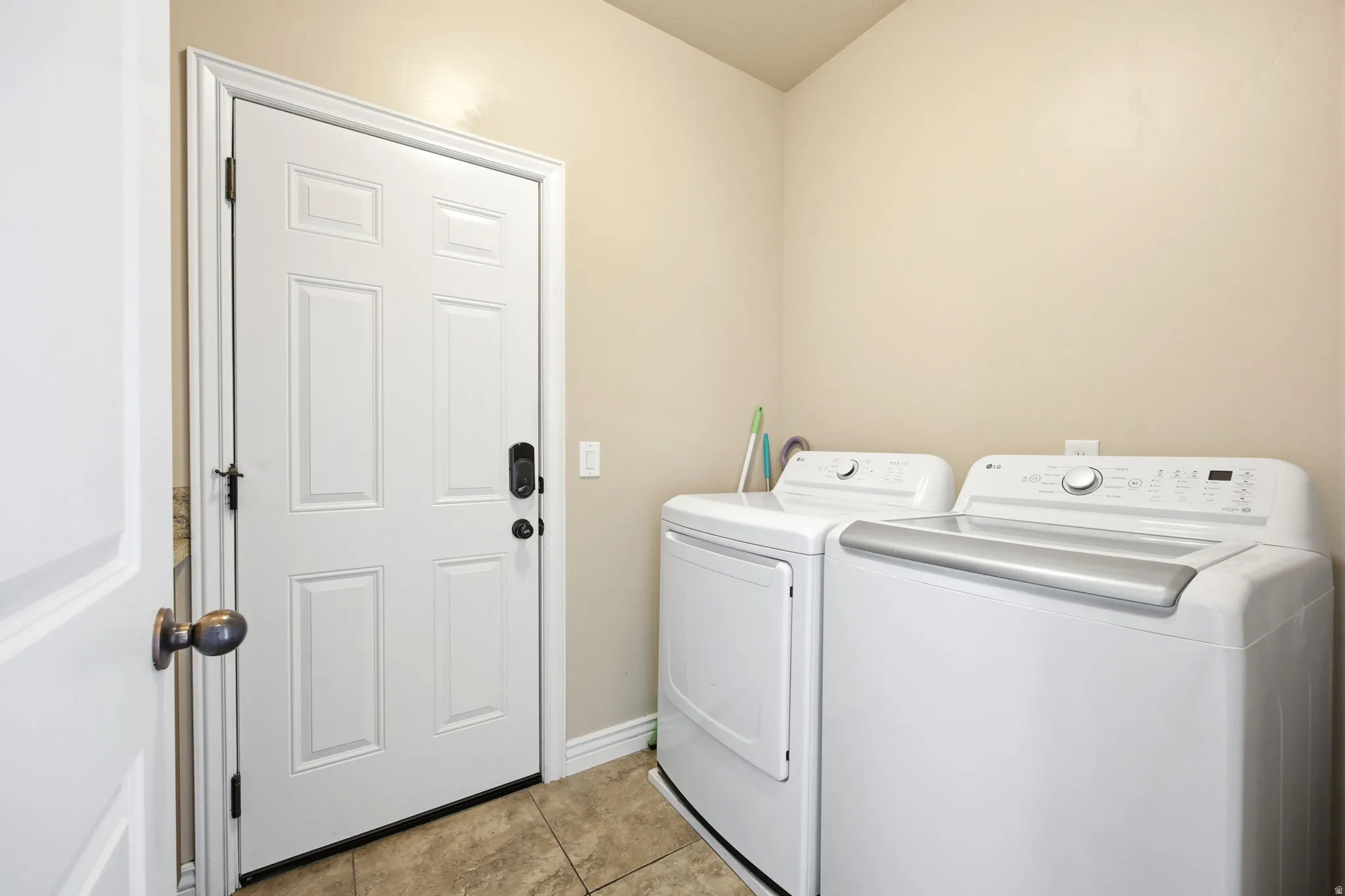 Utility room featuring tile flooring, neutral wall paint, and a white paneled door with dark hardware