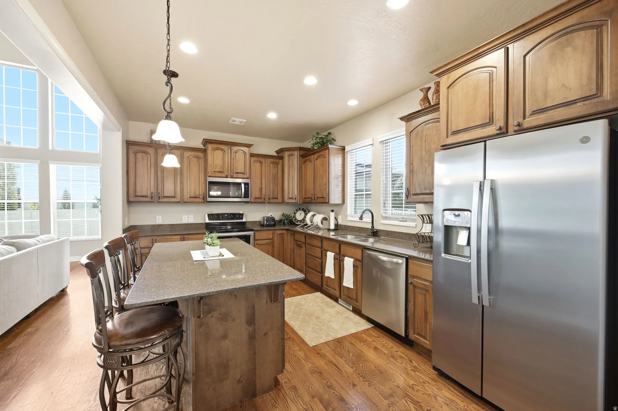 Spacious kitchen featuring an island with seating, wood-finish cabinetry, stainless steel appliances, and a double basin sink