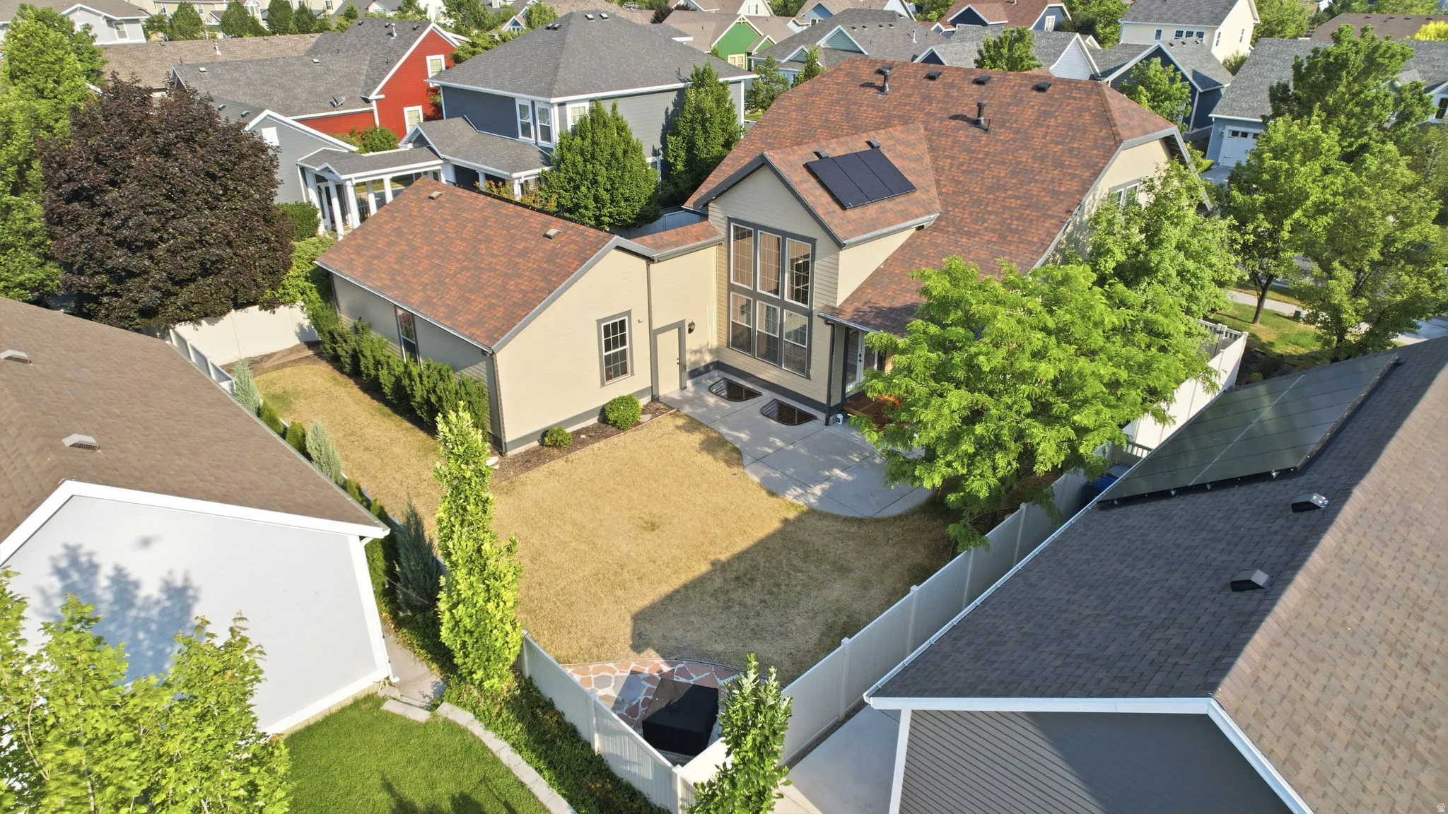 Residence featuring a light-colored exterior, brown shingle roof, solar panels, and a multi-pane window wall