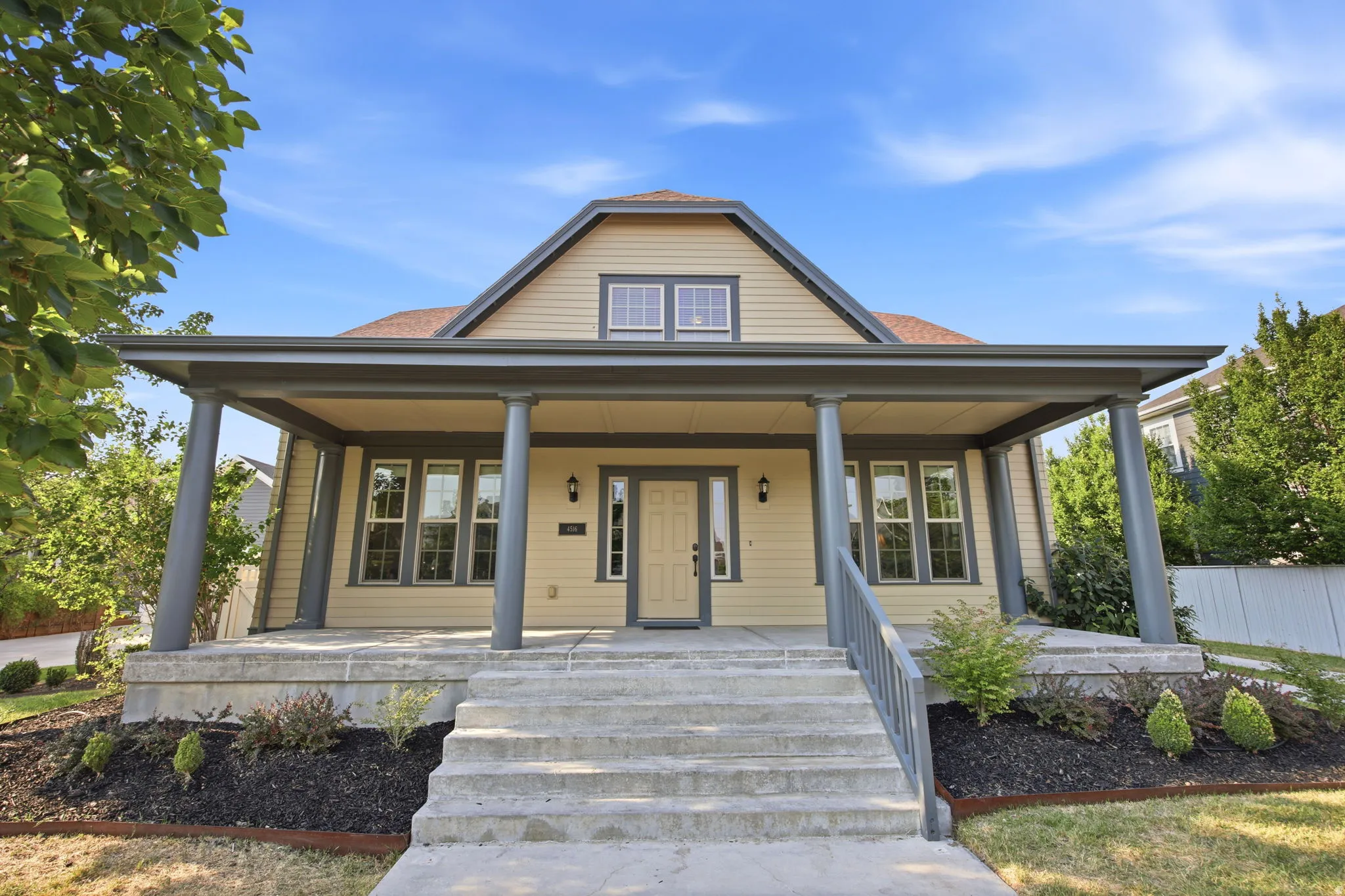 Craftsman-style facade featuring a covered front porch with substantial columns, concrete steps, and a decorative front door