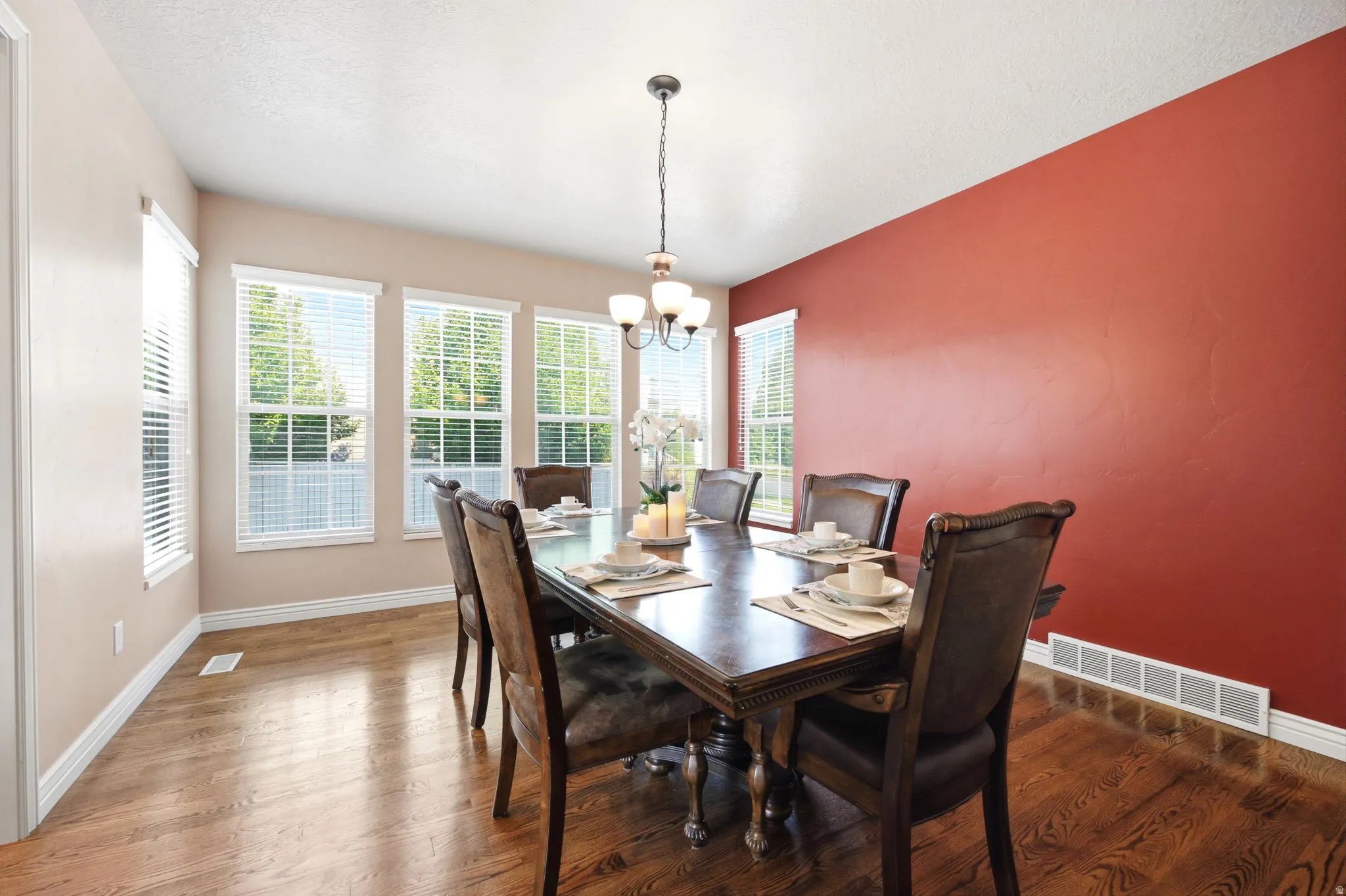 Dining area featuring rich wood-finish flooring and a red accent wall