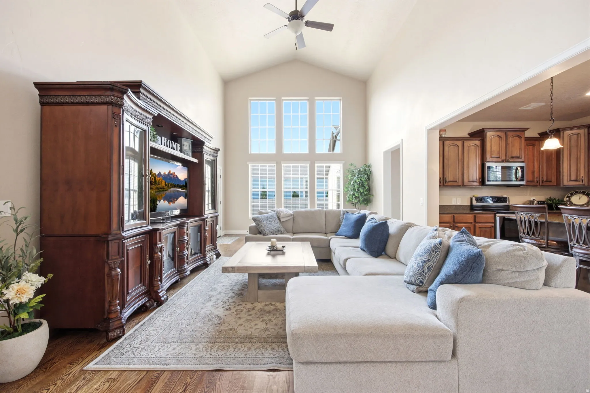 Vaulted ceiling in living area featuring large picture windows, wood-finish flooring, and recessed lighting