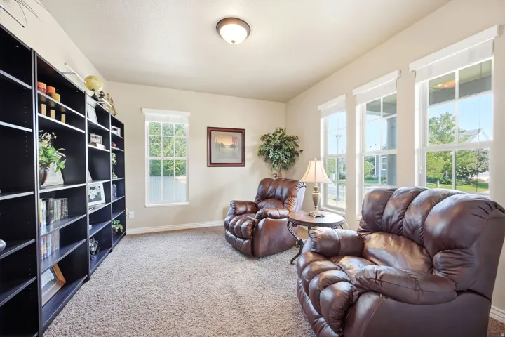 Bright interior room featuring a wall of built-in shelving, four windows providing natural light, and neutral wall paint