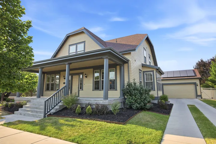 Traditional-style residence featuring a covered front porch with substantial columns, concrete steps with a black metal railing, and a gabled roofline