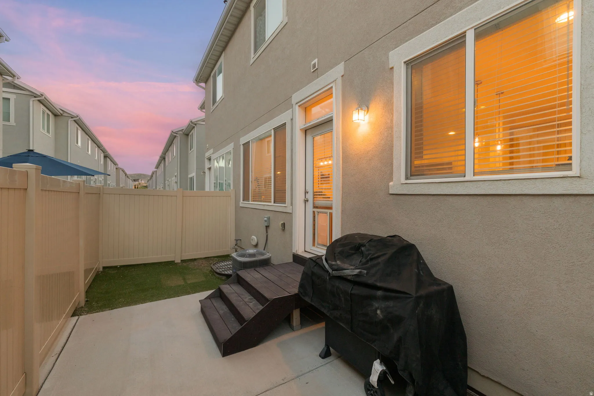 Private patio area featuring a concrete slab, wood-finish steps, and a stucco exterior