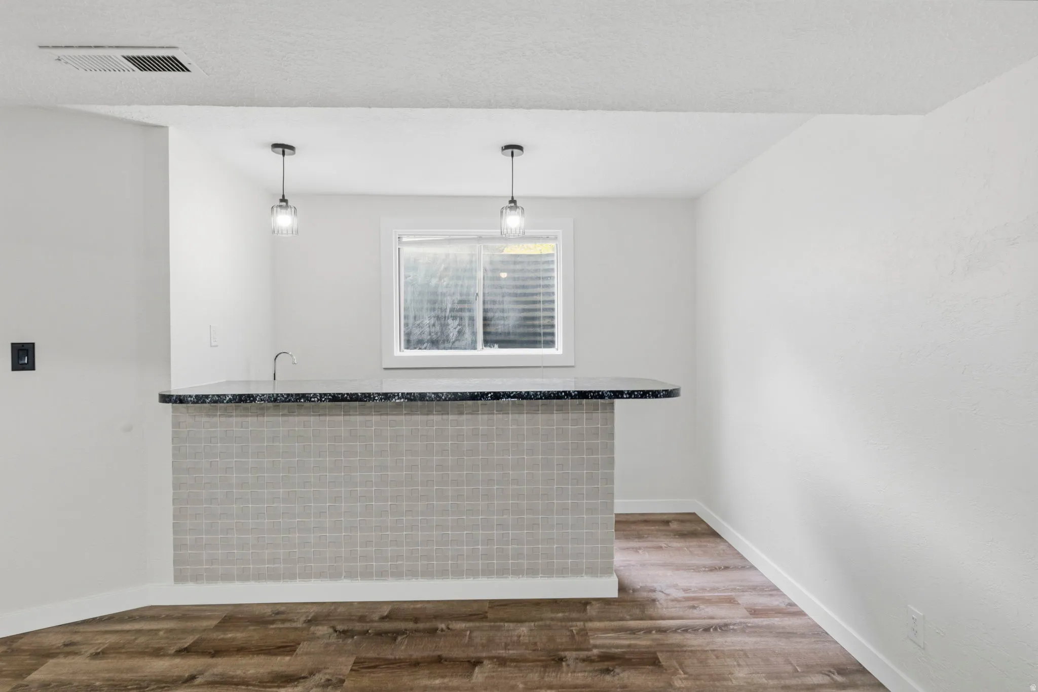 Built-in bar with a dark countertop and square-tiled facade