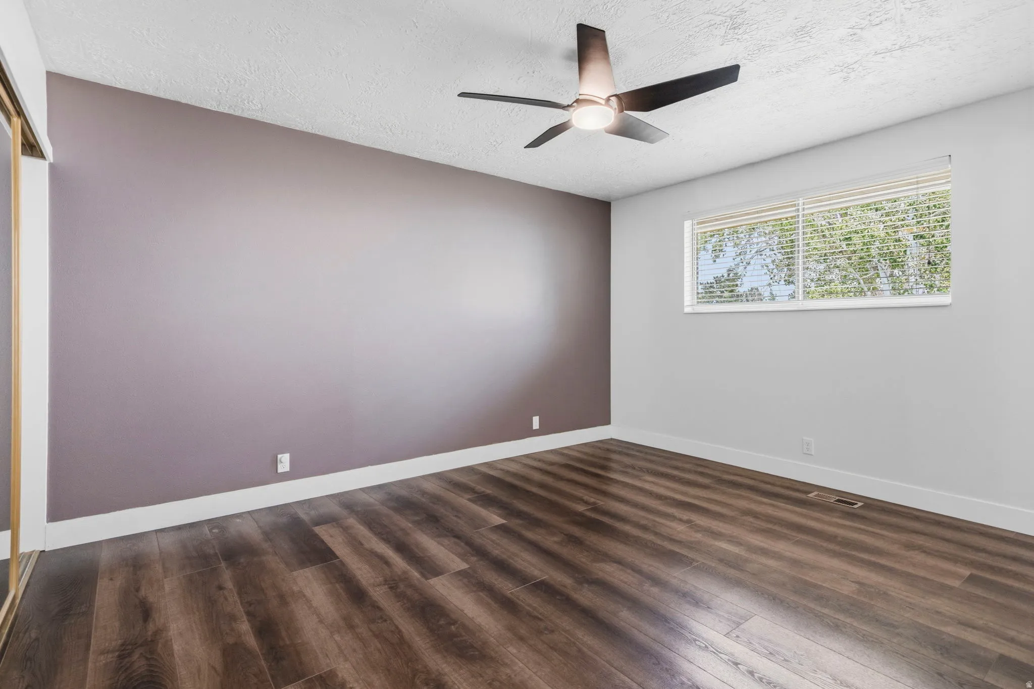 Bedroom featuring wood-finish flooring, a contemporary ceiling fan, and a wide window with blinds