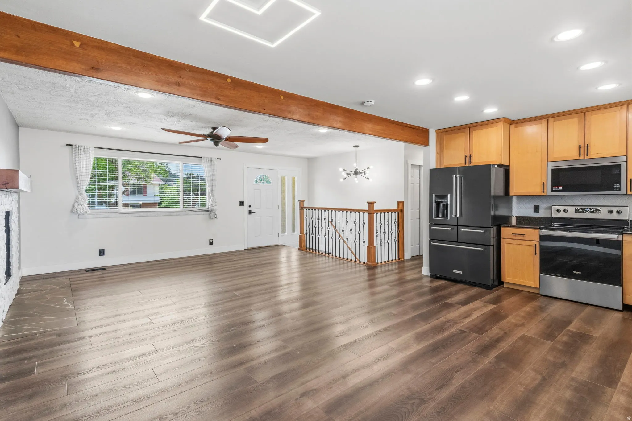 Open-concept living area featuring wood-finish flooring, a white brick fireplace, a ceiling fan, and recessed lighting