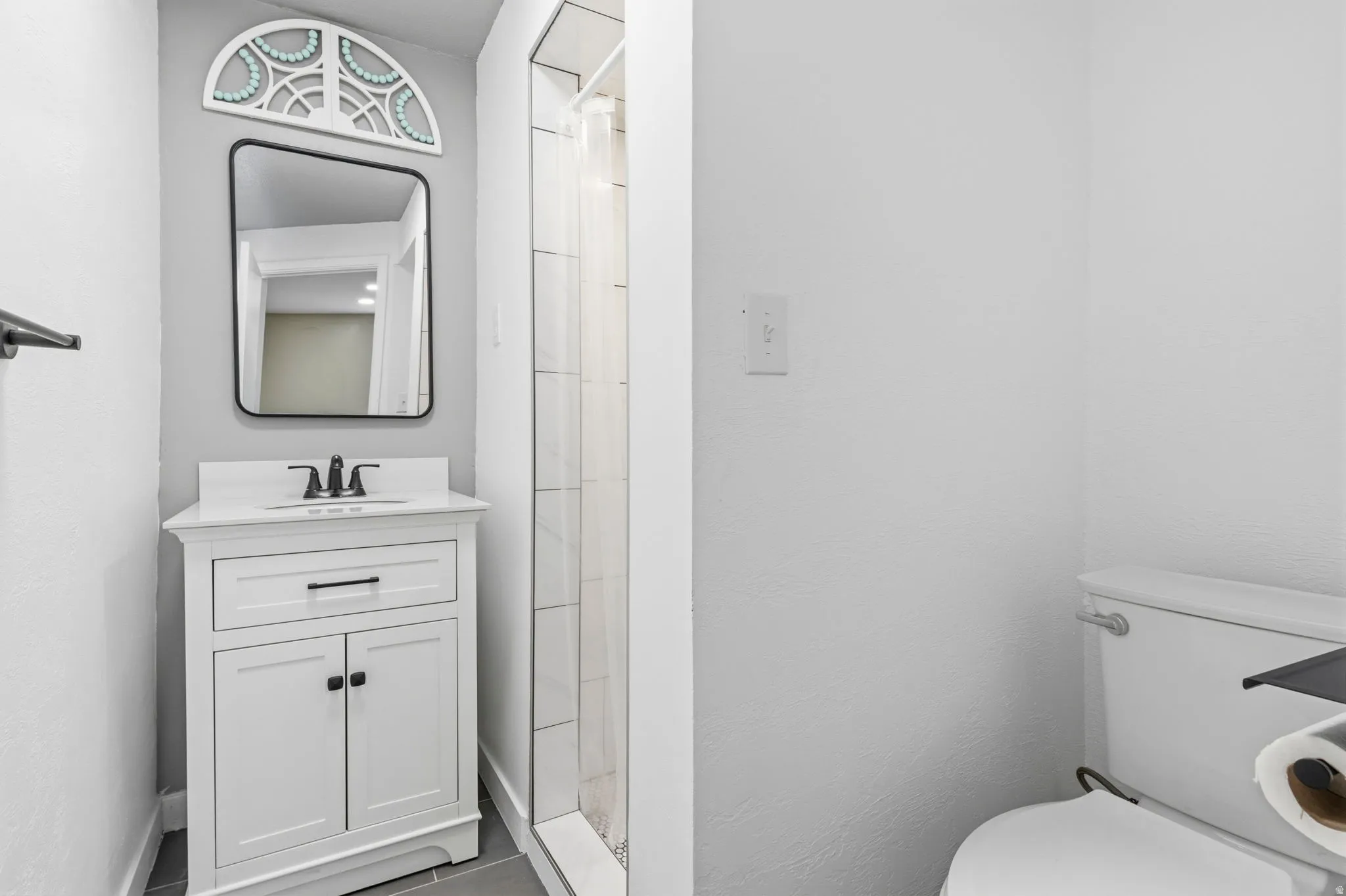 Contemporary bathroom featuring a white vanity with integrated sink, matte black faucet, and a rectangular framed mirror