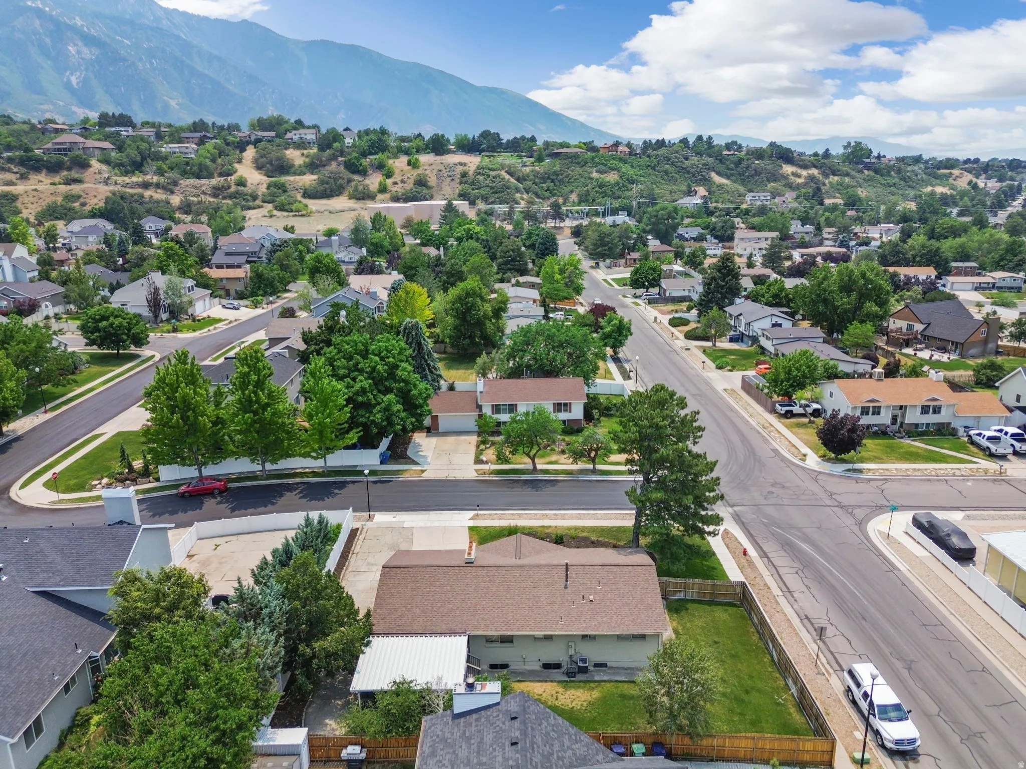 Residential neighborhood featuring mature trees and mountain scenery