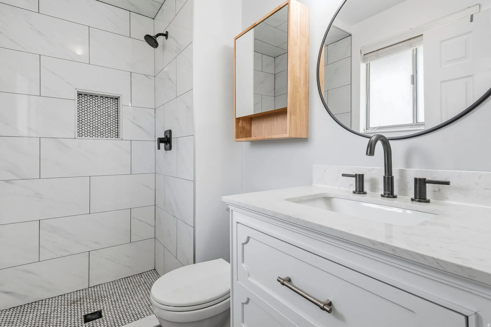 Bathroom featuring a white vanity with a stone-finish countertop, undermount sink, and matte black fixtures