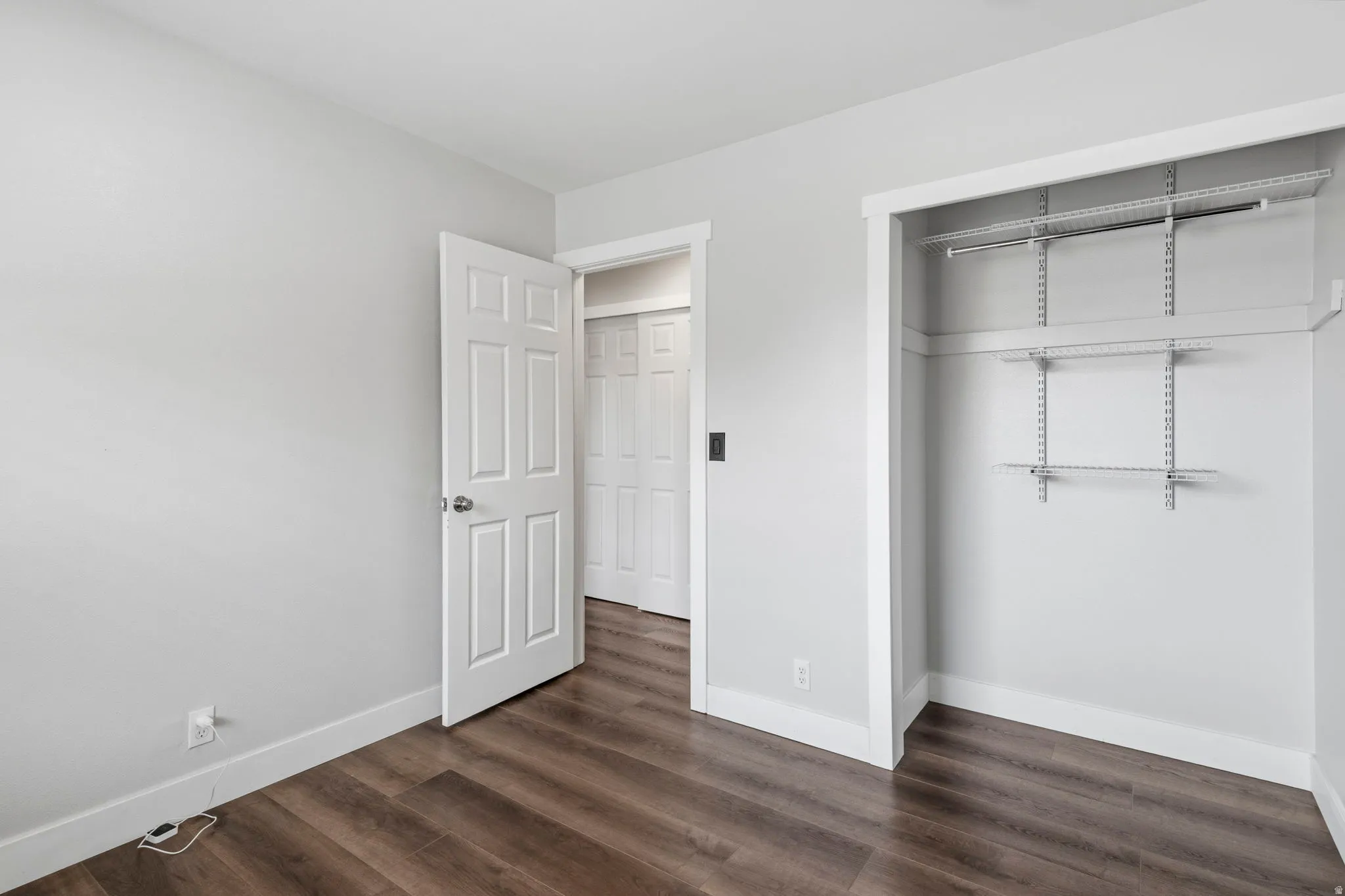 Room featuring wood-finish flooring, light gray wall paint, and white baseboards