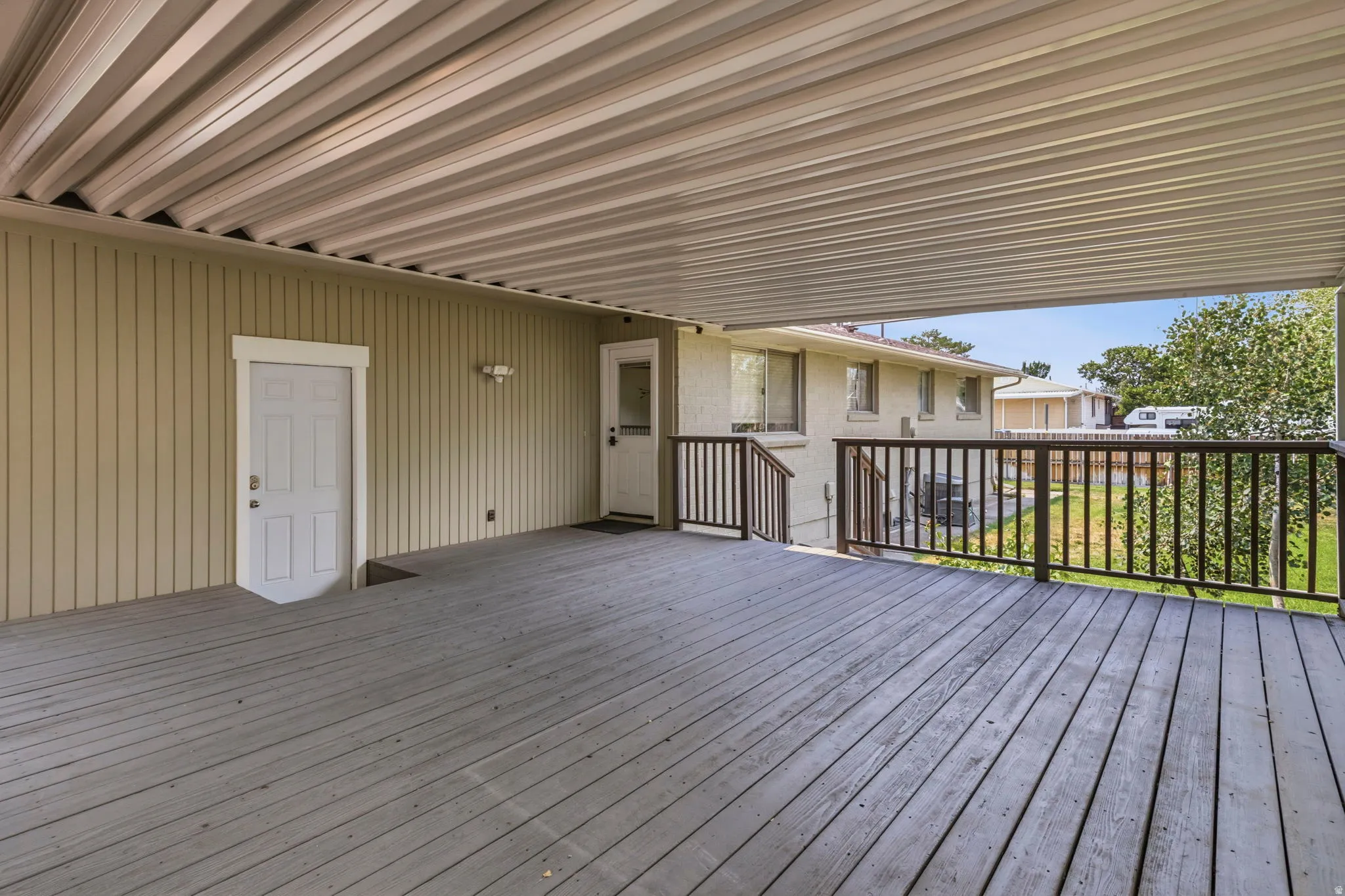 Spacious covered deck featuring wood-finish flooring, a full ceiling, and dark-stained railings