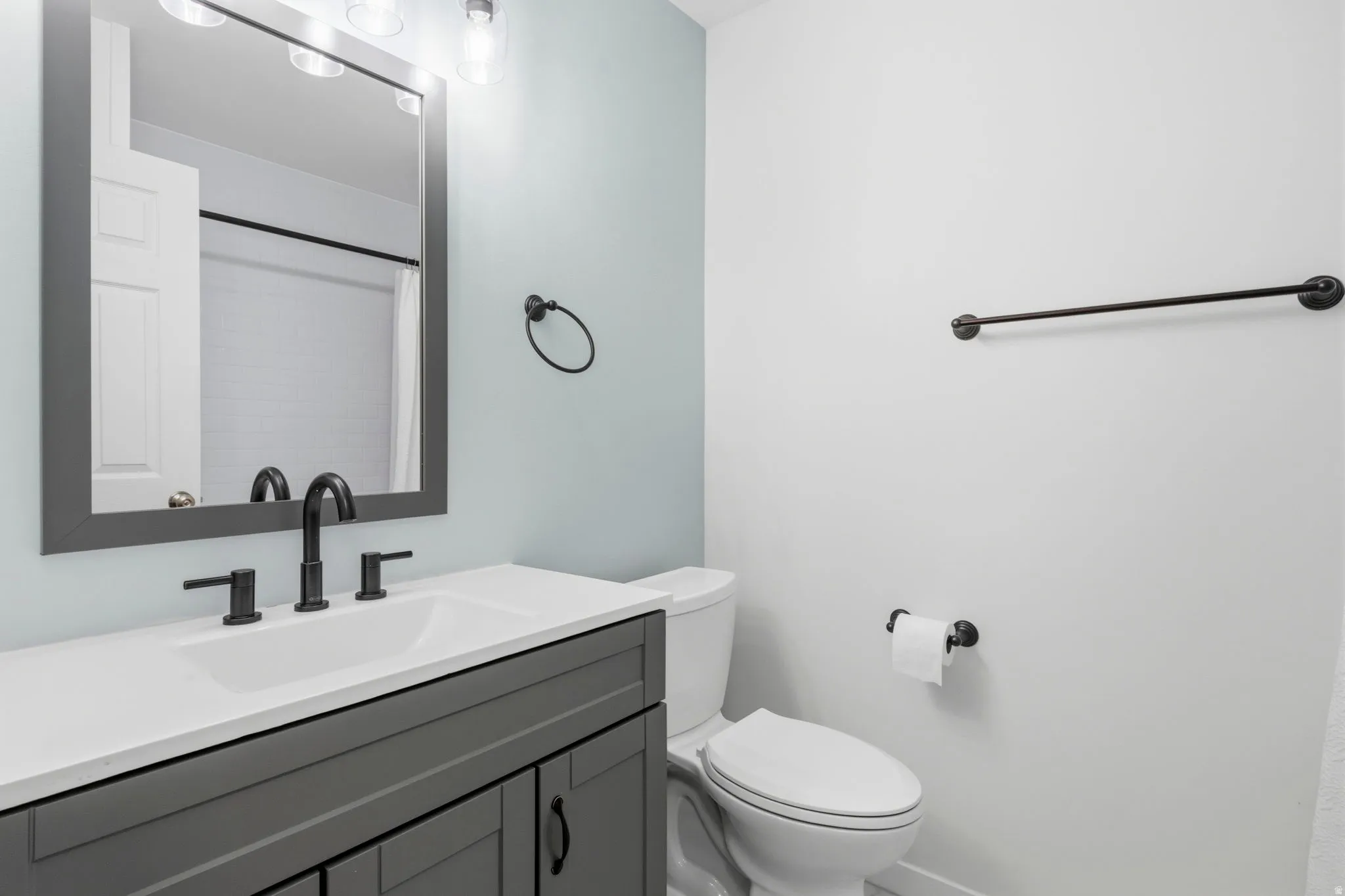 Bathroom featuring a gray vanity with a white countertop, undermount sink, and matte black fixtures