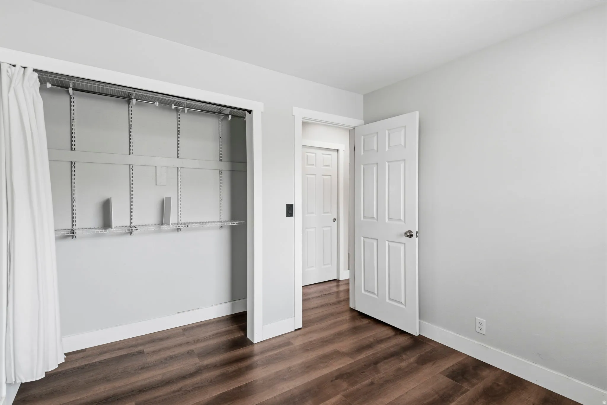 Interior room featuring wood-finish flooring, light gray wall paint, and white trim