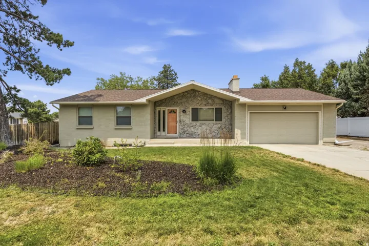 Ranch-style residence featuring a prominent stone facade accent, a light-colored brick exterior, and a two-car garage with an overhead door