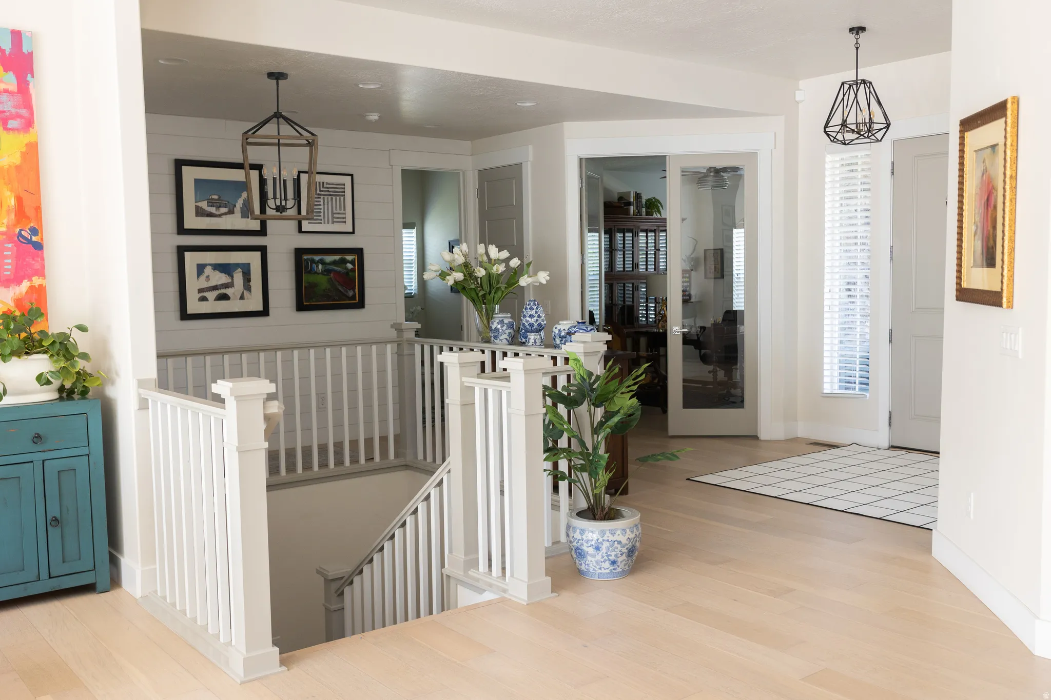 Entry foyer featuring wood-finish flooring, white shiplap accent wall, staircase with white railings, and a pair of glass french doors