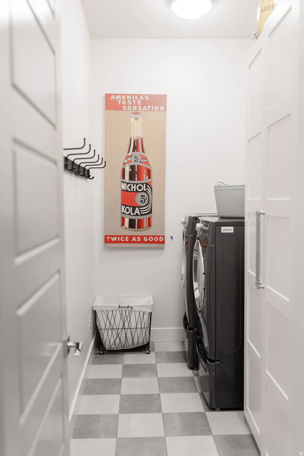 Dedicated laundry area featuring checkerboard-patterned flooring and integrated cabinetry with brushed metal hardware
