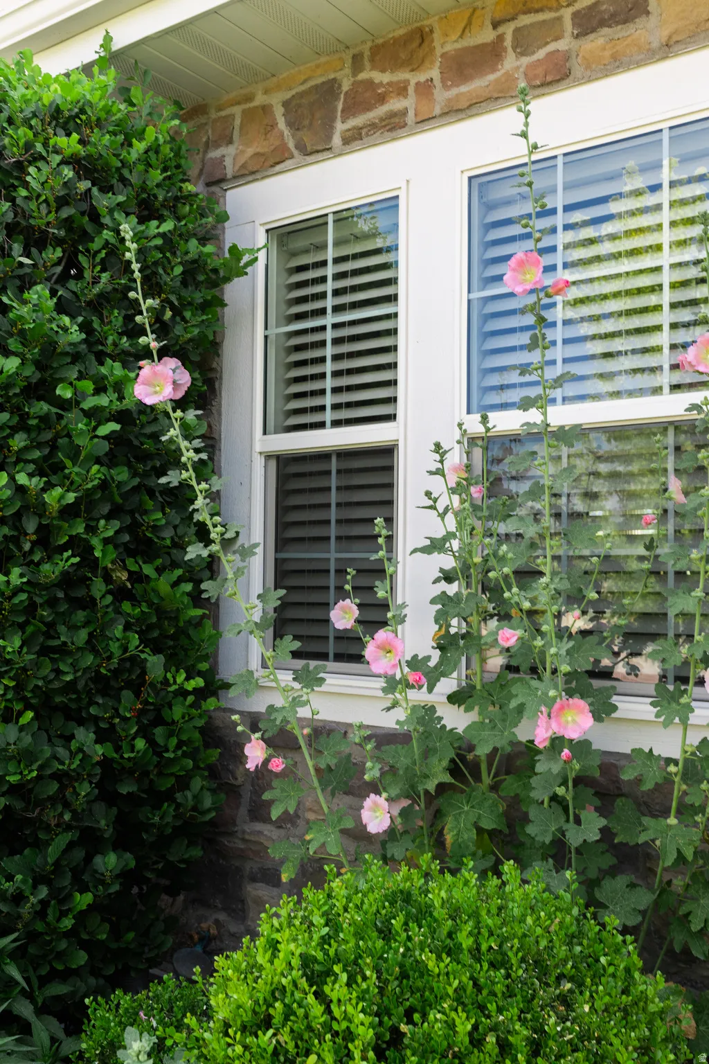 Over-grouted Stone veneer siding accenting the exterior, complemented by white-framed windows with louvered blinds