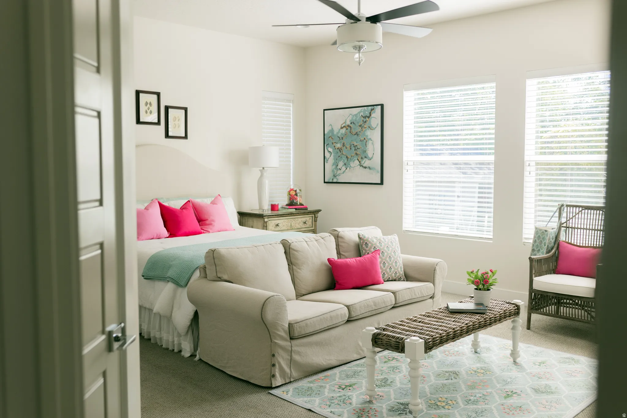 Primary bedroom on main floor. Bright room featuring a ceiling fan, dual windows with blinds, and light-colored walls