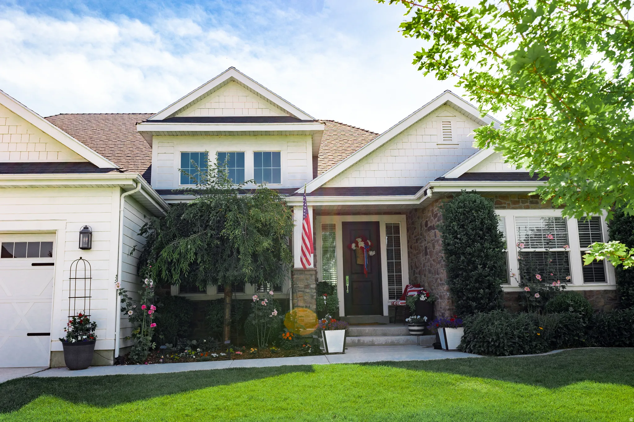 Contemporary exterior featuring white horizontal siding, shake siding, stone accents, a dark entry door, and a three-car garage with transom windows