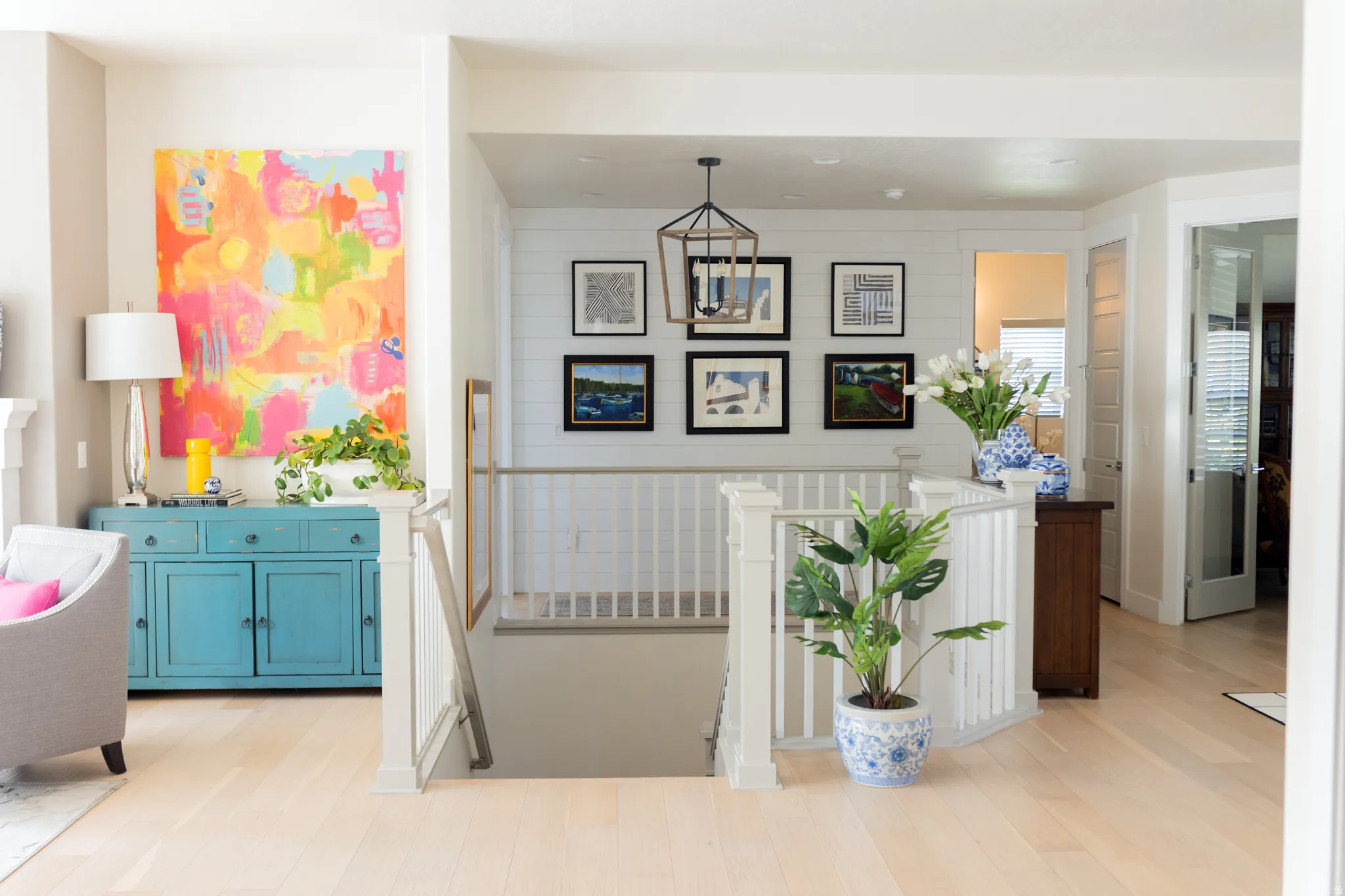 Light wood-finish flooring throughout, featuring a central staircase with white balusters and newel posts
