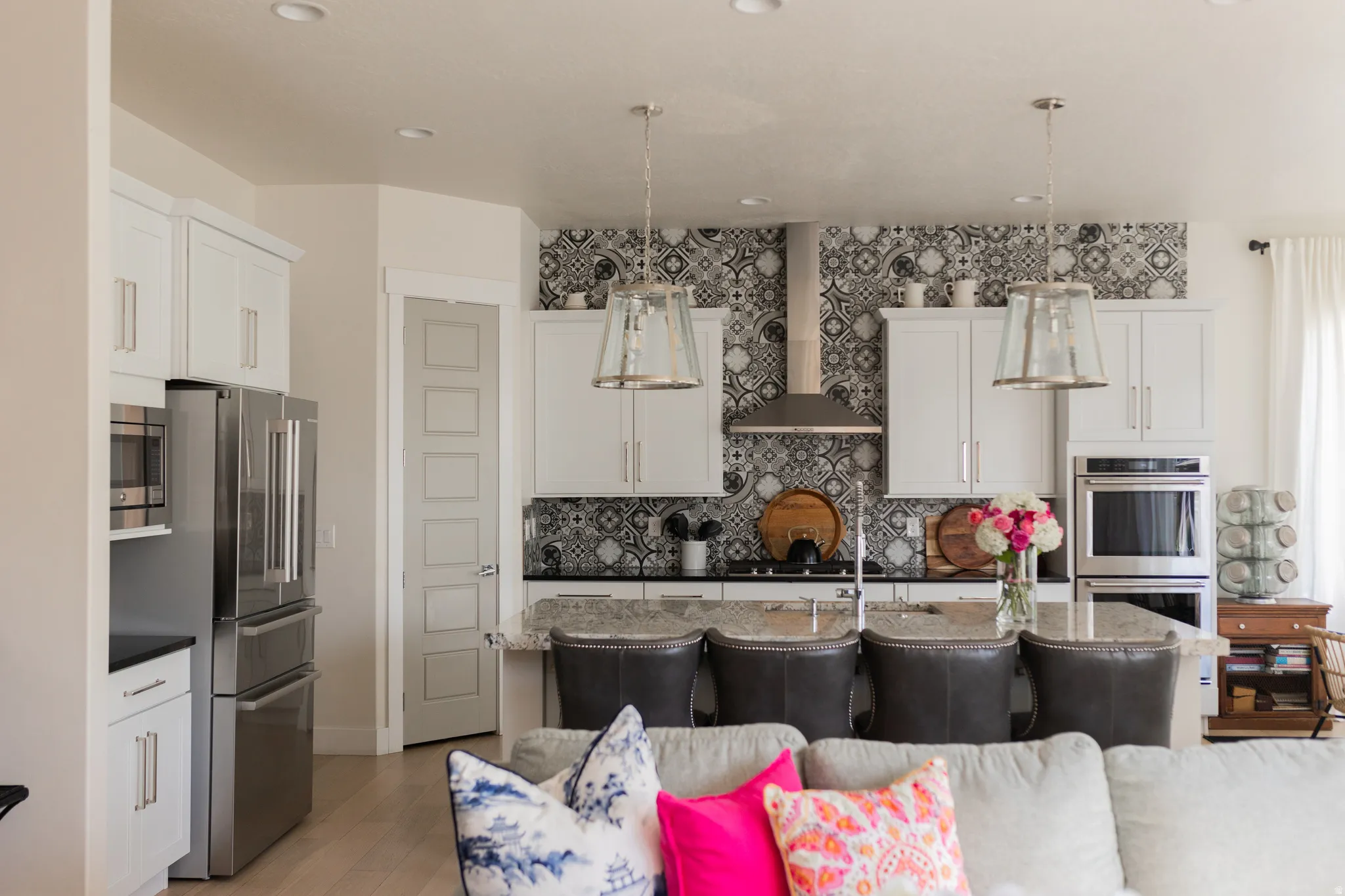 Kitchen featuring white cabinetry, a decorative tile backsplash, stainless steel appliances, a kitchen island with seating, and pendant lighting