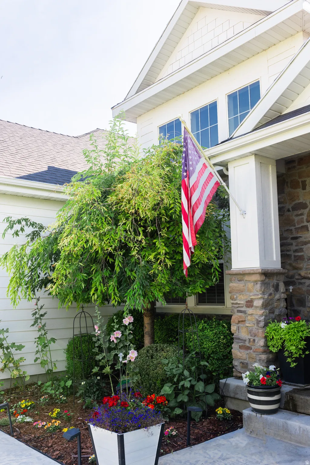 Stone veneer accents, white siding, and a gabled roofline define the exterior
