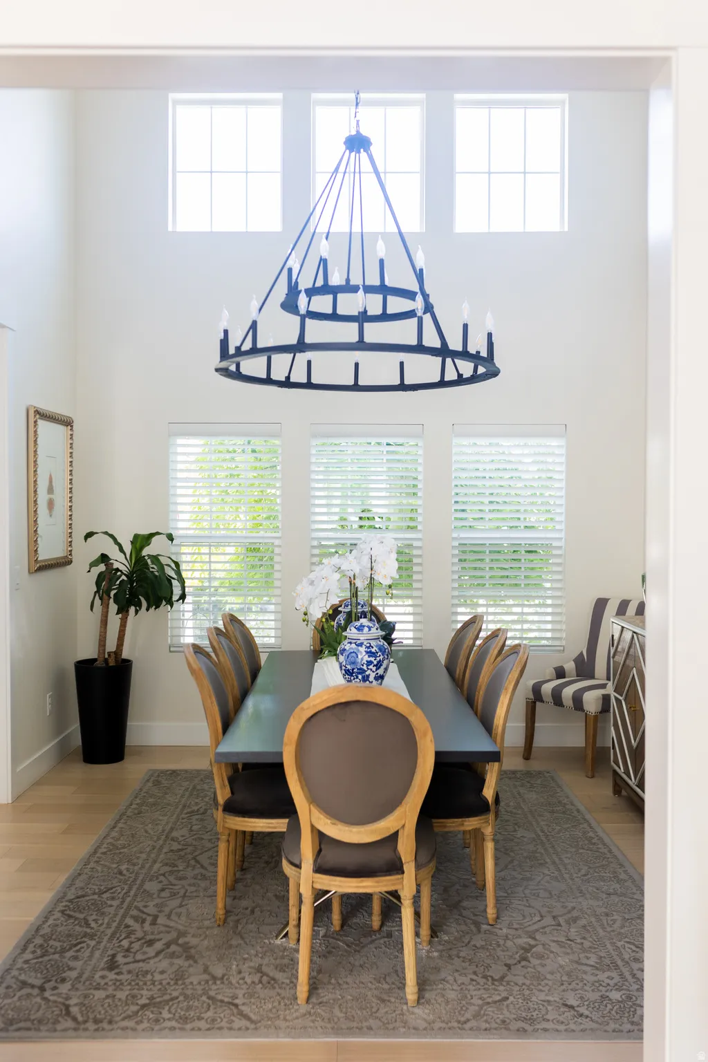 Dining area featuring a two-story ceiling, a large multi-tiered chandelier, and light wood-finish flooring