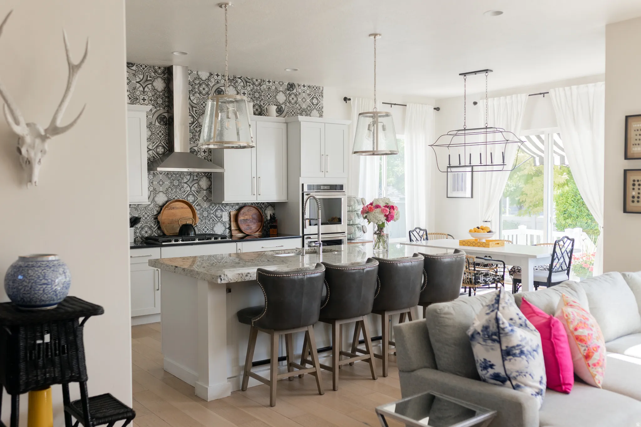 Open-concept kitchen and dining area featuring a kitchen island with seating, pendant lighting, built-in appliances, and light wood-finish flooring