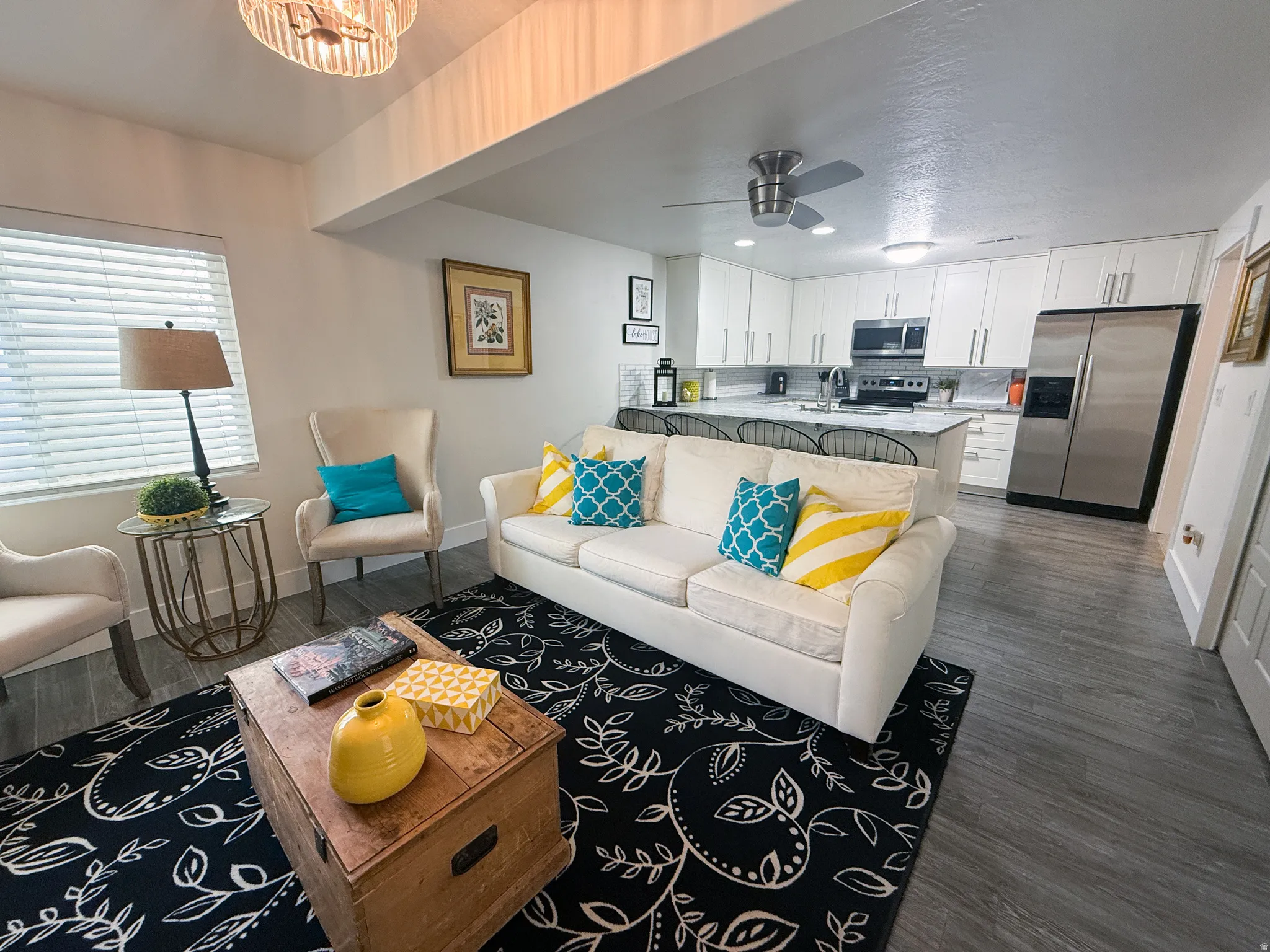 Entrance to Mother-in-law apartment with an open-concept living space featuring wood-finish flooring, a contemporary kitchen with white cabinetry and stainless steel appliances, a kitchen island with seating, and a ceiling fan