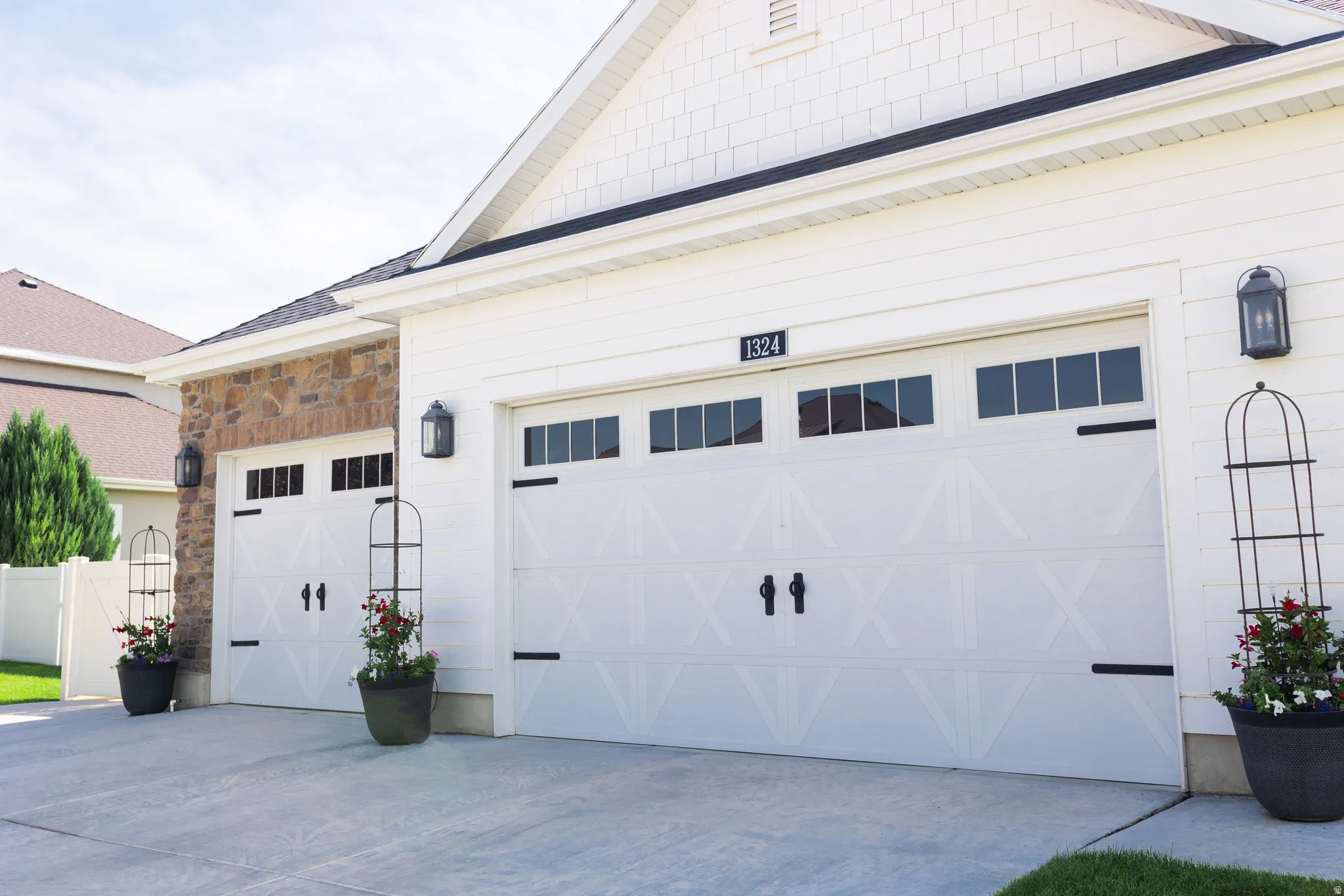 Two white garage doors with black hardware and upper window panels