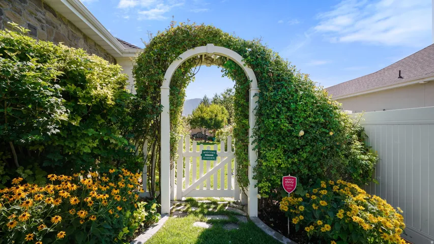 Archway entry with a white picket gate and lush climbing greenery