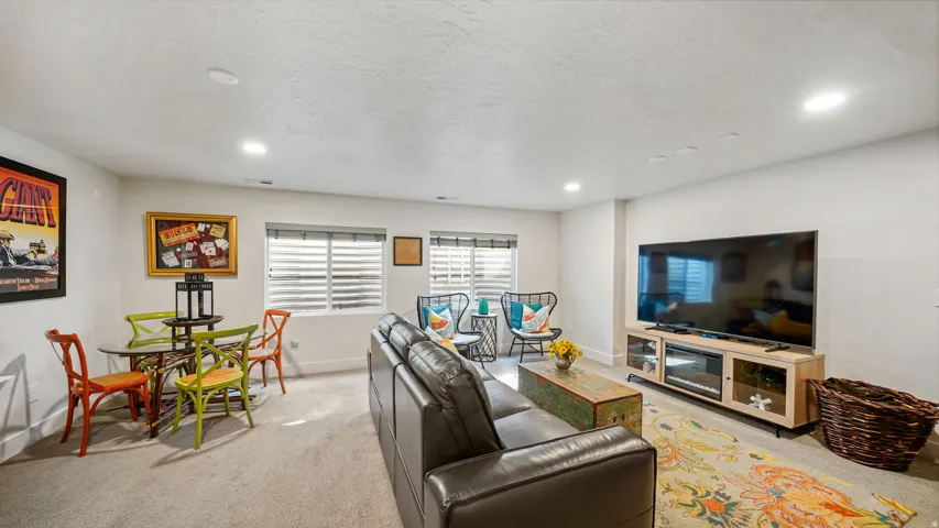 Spacious living area featuring light-toned carpeting and recessed lighting