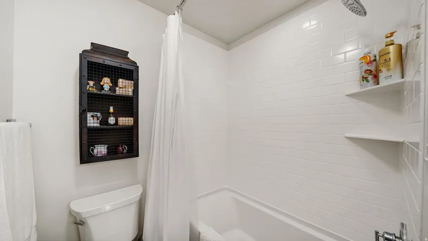 Bathtub with subway tile surround, integrated shower head, and two built-in wall shelves
